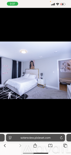 A bedroom with a bed, nightstand, and a painting on the wall.