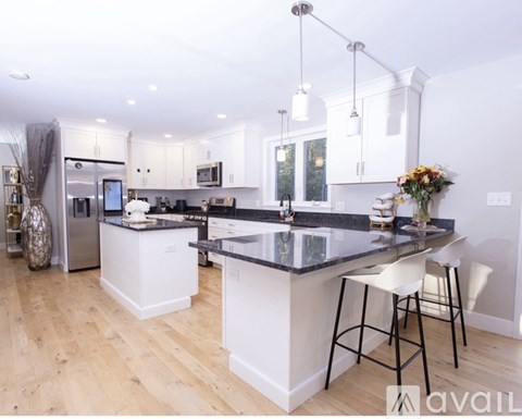 A kitchen with a black counter top and white cabinets.