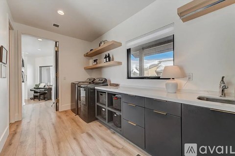 A kitchen with black cabinets and a wooden floor.