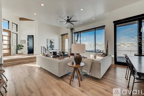 A modern living room with a large sofa and a view of the mountains.