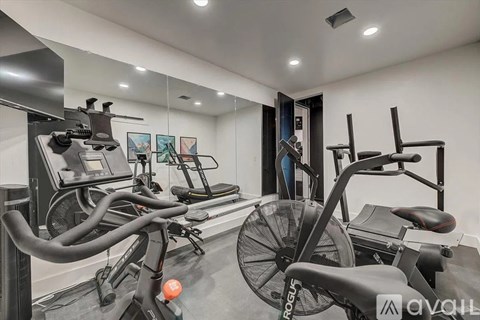 A gym with a row of exercise bikes and a fan.