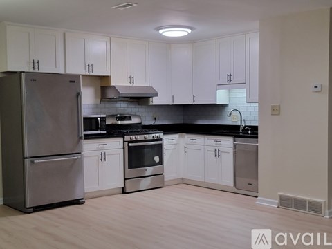 A kitchen with white cabinets and a stainless steel refrigerator.