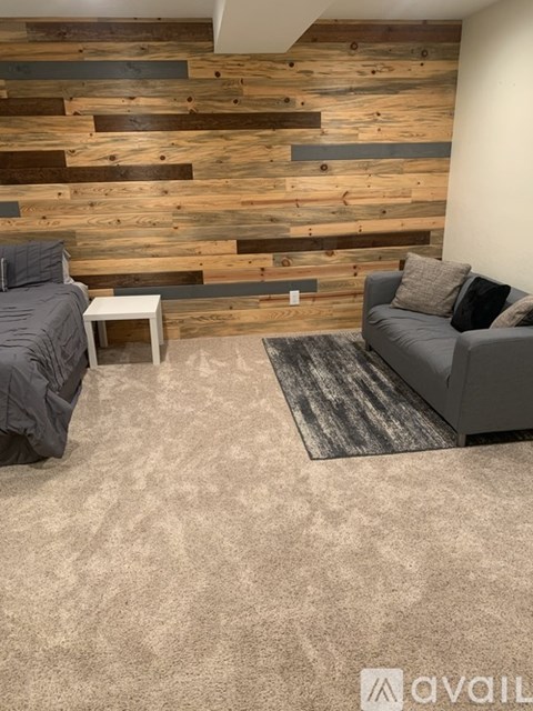 A living room with a grey couch and a wooden wall.