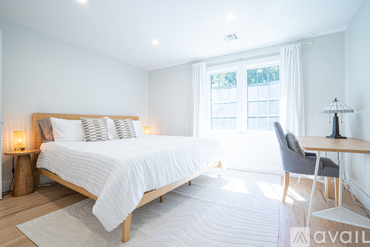 A bedroom with a large bed, a chair, and a desk.