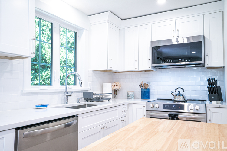 A kitchen with white cabinets and a wooden countertop.
