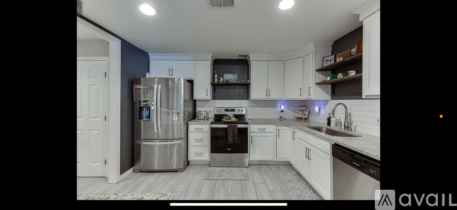 A kitchen with white cabinets and a stainless steel refrigerator.