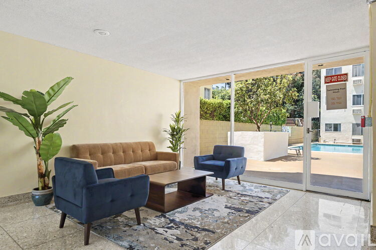 A living room with a brown sofa, blue armchair, and a large plant.