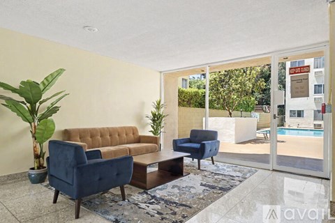 A living room with a brown sofa, blue armchair, and a large plant.