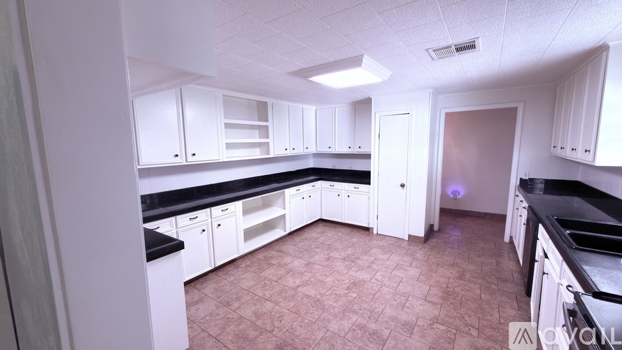 A kitchen with white cabinets and black countertops.