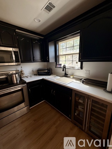 A kitchen with black cabinets and stainless steel appliances.