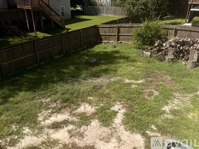 A backyard with a wooden fence and a grassy area.