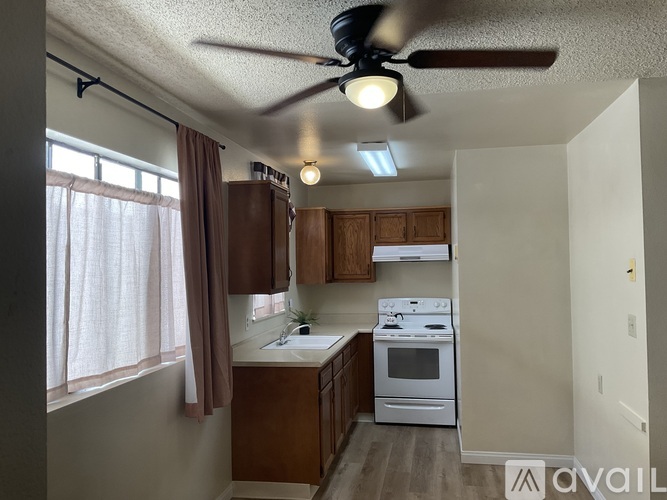 A kitchen with a fan and a window with curtains.