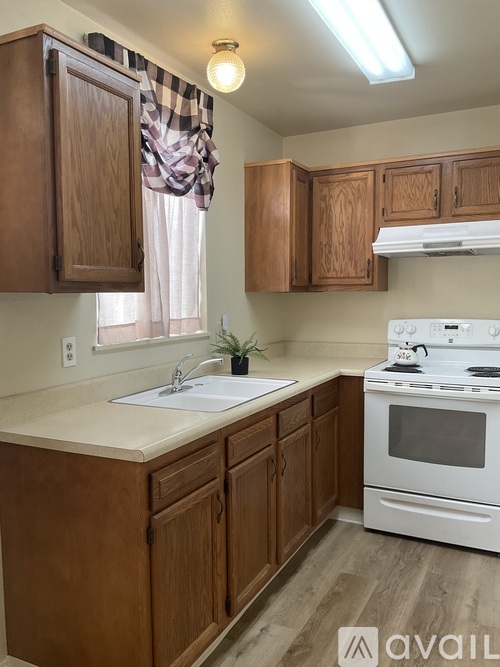 A kitchen with wooden cabinets and a white stove top oven.