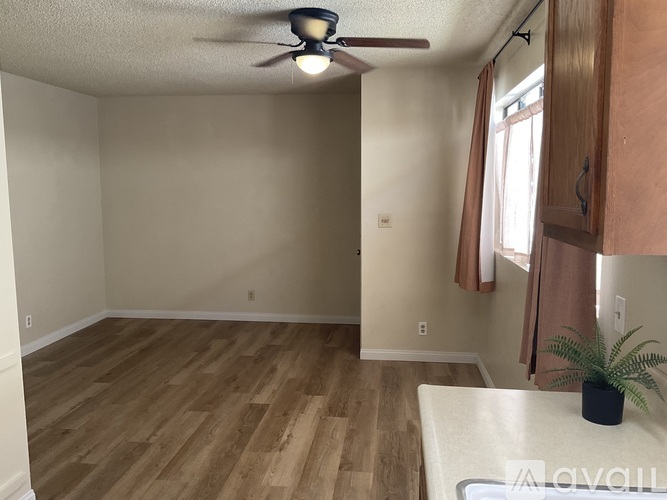 A room with a ceiling fan and wooden flooring.
