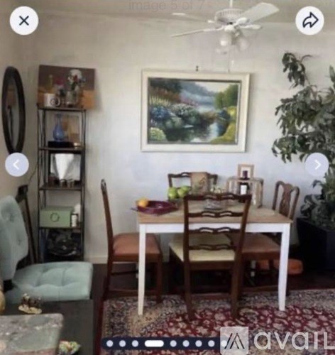 A dining room with a table set for two and a painting on the wall.