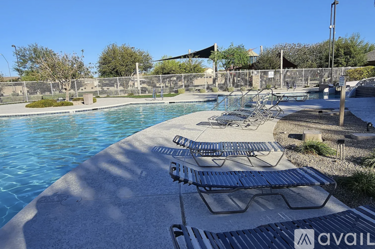 A pool with sun loungers and a metal fence.