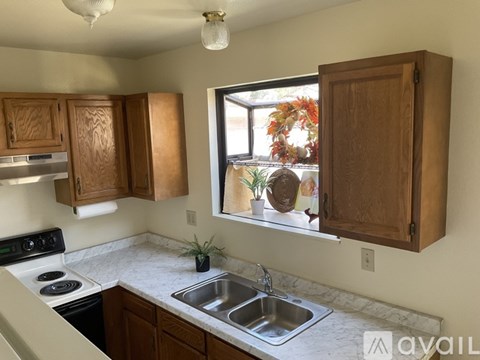 A kitchen with wooden cabinets and a window overlooking a garden.