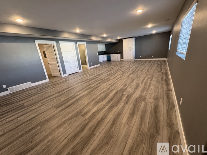 A spacious room with wooden flooring and multiple doors.