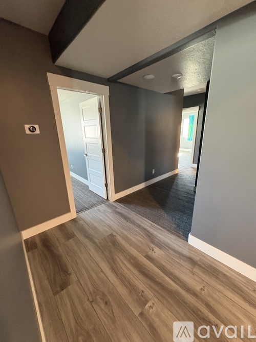 A hallway with a wooden floor and a white door.