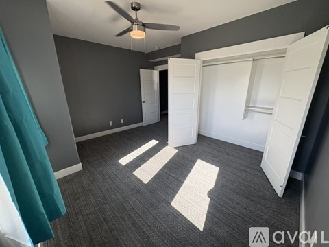 A room with a ceiling fan and two open doors.
