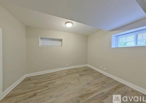A room with wooden flooring and a window with blinds.
