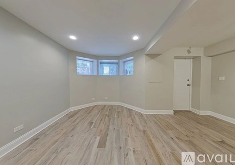 A spacious room with wooden flooring and a skylight.