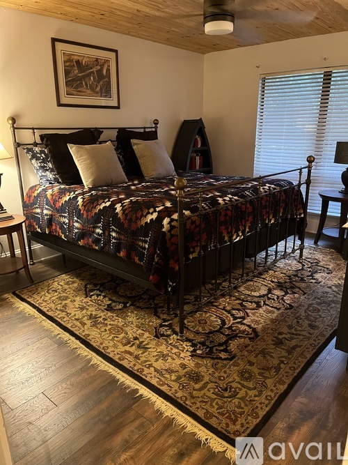 A bedroom with a large bed and a rug on the floor.