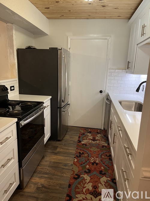 A kitchen with a black fridge and a white door.