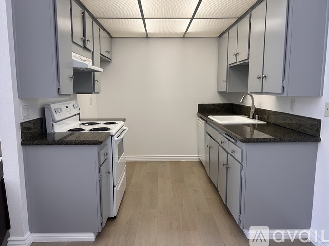 A kitchen with white cabinets and a black countertop.
