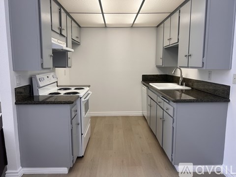 A kitchen with white cabinets and a black countertop.