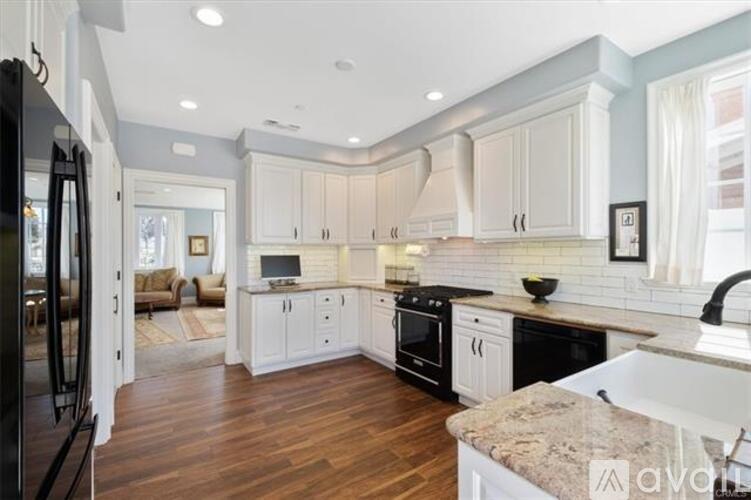 A kitchen with white cabinets and a black refrigerator.