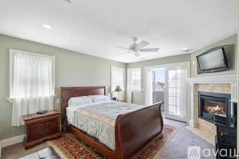 A bedroom with a large bed, a fireplace, and a television.
