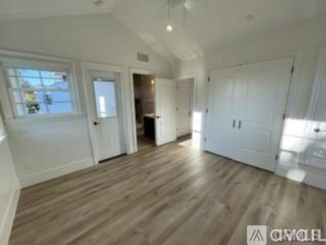 A spacious room with wooden flooring and white walls.