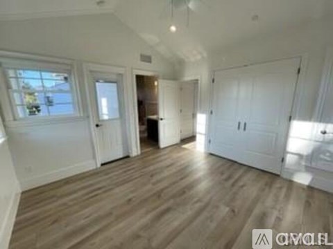 A spacious room with wooden flooring and white walls.