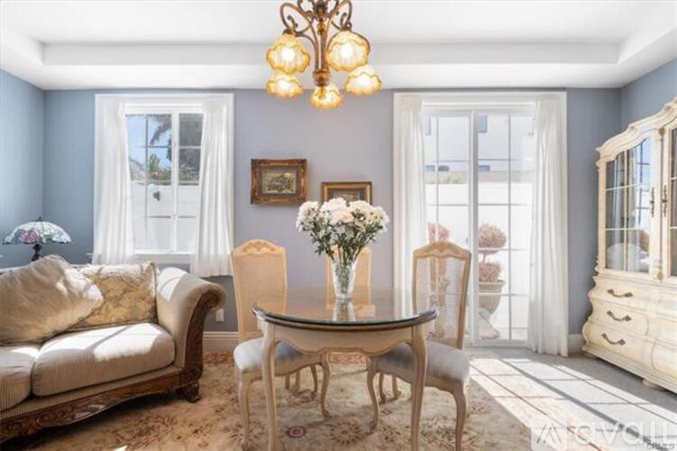 A dining room with a table set for two and a couch.
