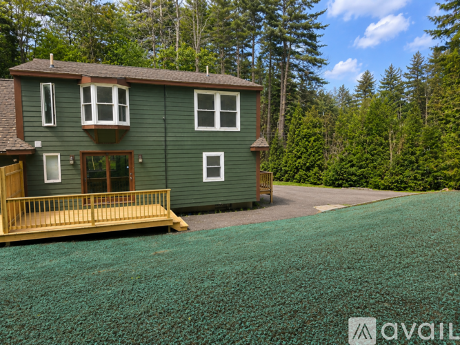 A house with a green lawn and trees in the background.