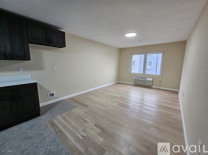 A spacious room with wooden flooring and a window.