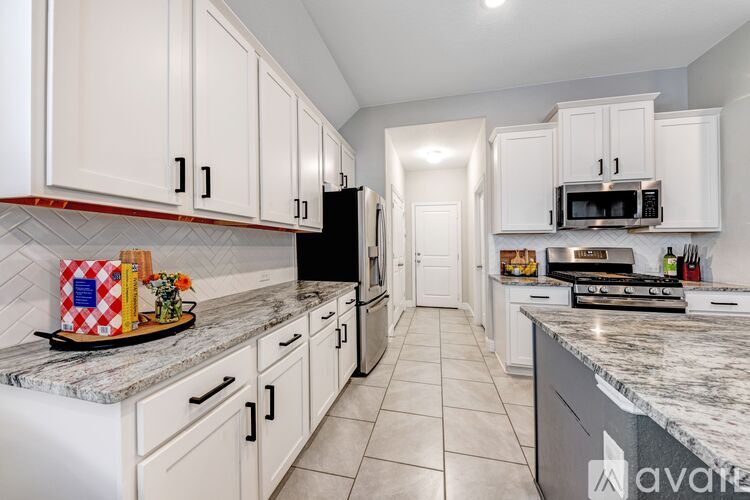 A kitchen with white cabinets and a marble countertop.