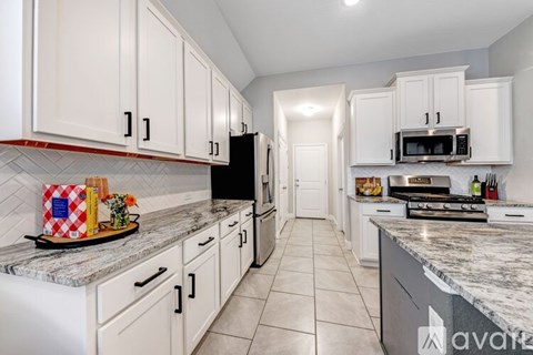 A kitchen with white cabinets and a marble countertop.