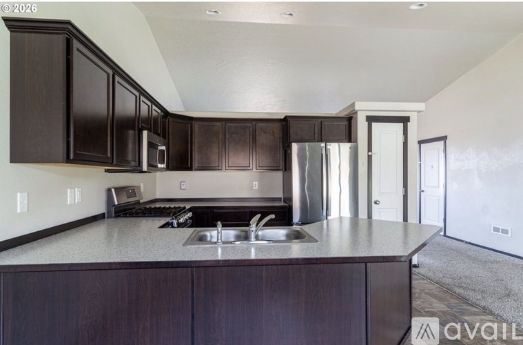 A kitchen with dark wood cabinets and a stainless steel refrigerator.