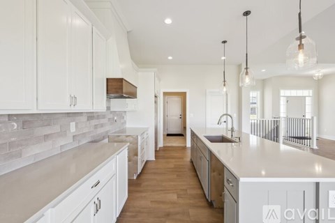 A modern kitchen with white cabinets and a wooden floor.