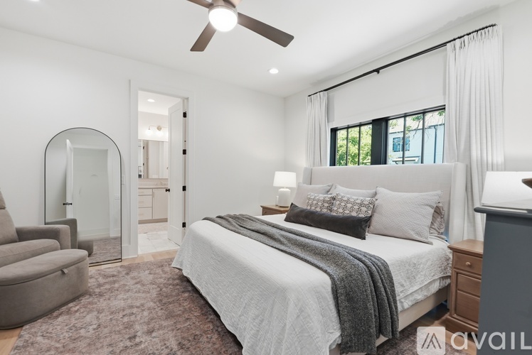 A bedroom with a large bed, a ceiling fan, and a chair.