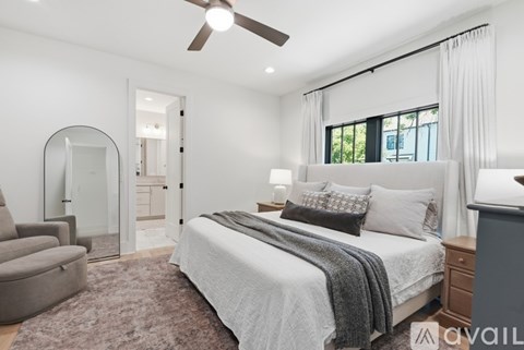 A bedroom with a large bed, a ceiling fan, and a chair.