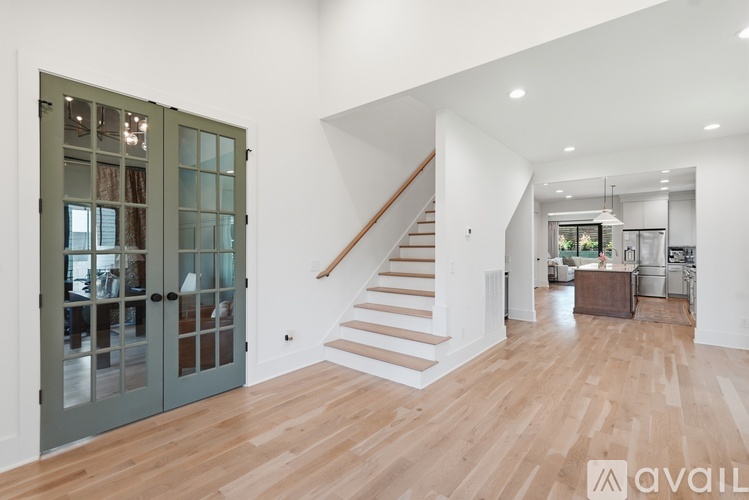 A spacious room with wooden floors and a staircase leading to the upper level.