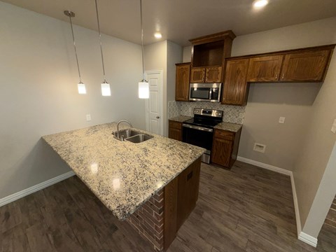A kitchen with granite countertops and wooden cabinets.