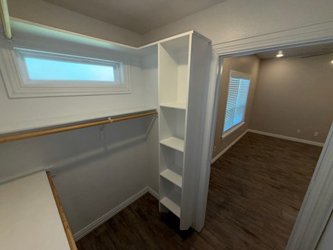 A small, empty room with a window and a shelf.