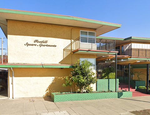 A building with a balcony and a tree in front of it.