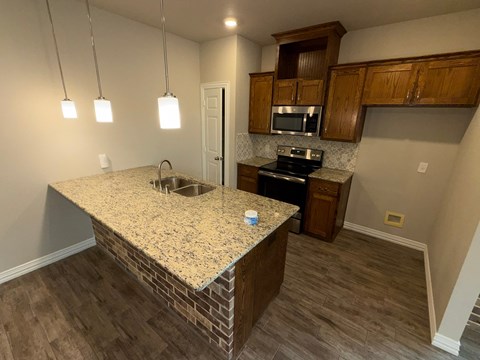 A kitchen with granite countertops and wooden cabinets.