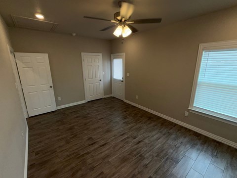 A room with a ceiling fan and wooden flooring.