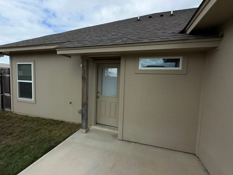 A house with a brown roof and tan siding with a brown door and window.